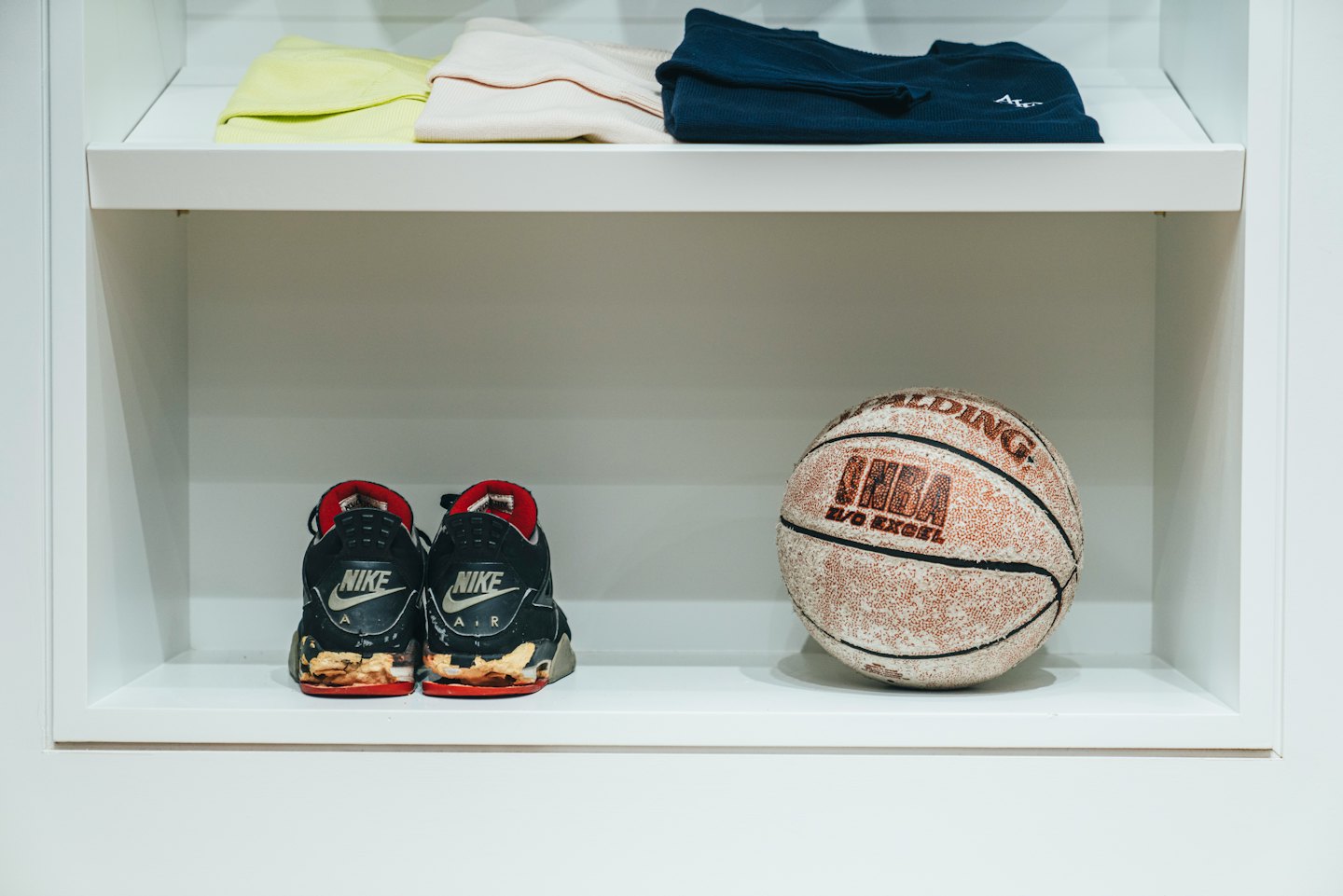 Black and red sneakers and basketball on a shelf.